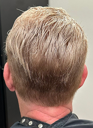 Back view of a short blond haircut with a tapered nape and ears visible