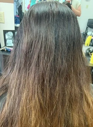 Back view of long dark brown hair with lighter ombré ends in a salon setting