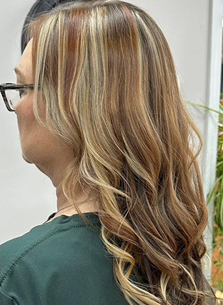 Side view of highlighted wavy hair with blonde and brown tones, worn with glasses.